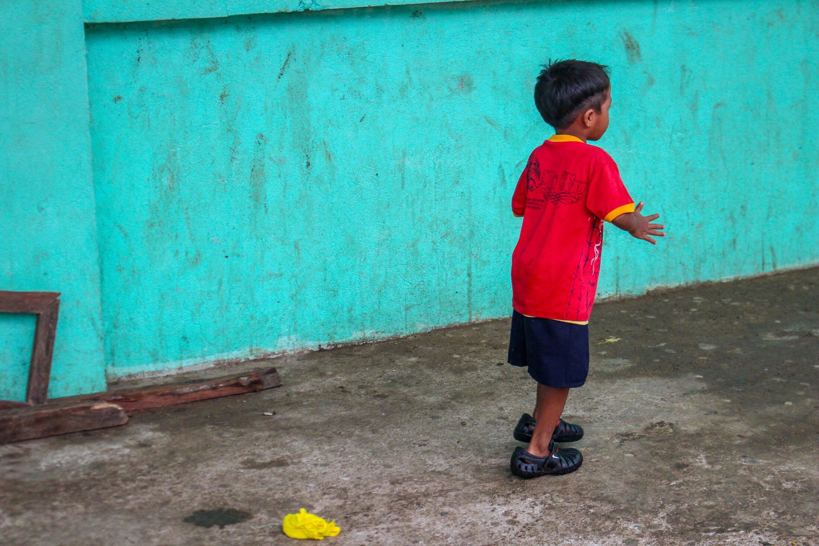 Child against a turquoise wall in Cebu