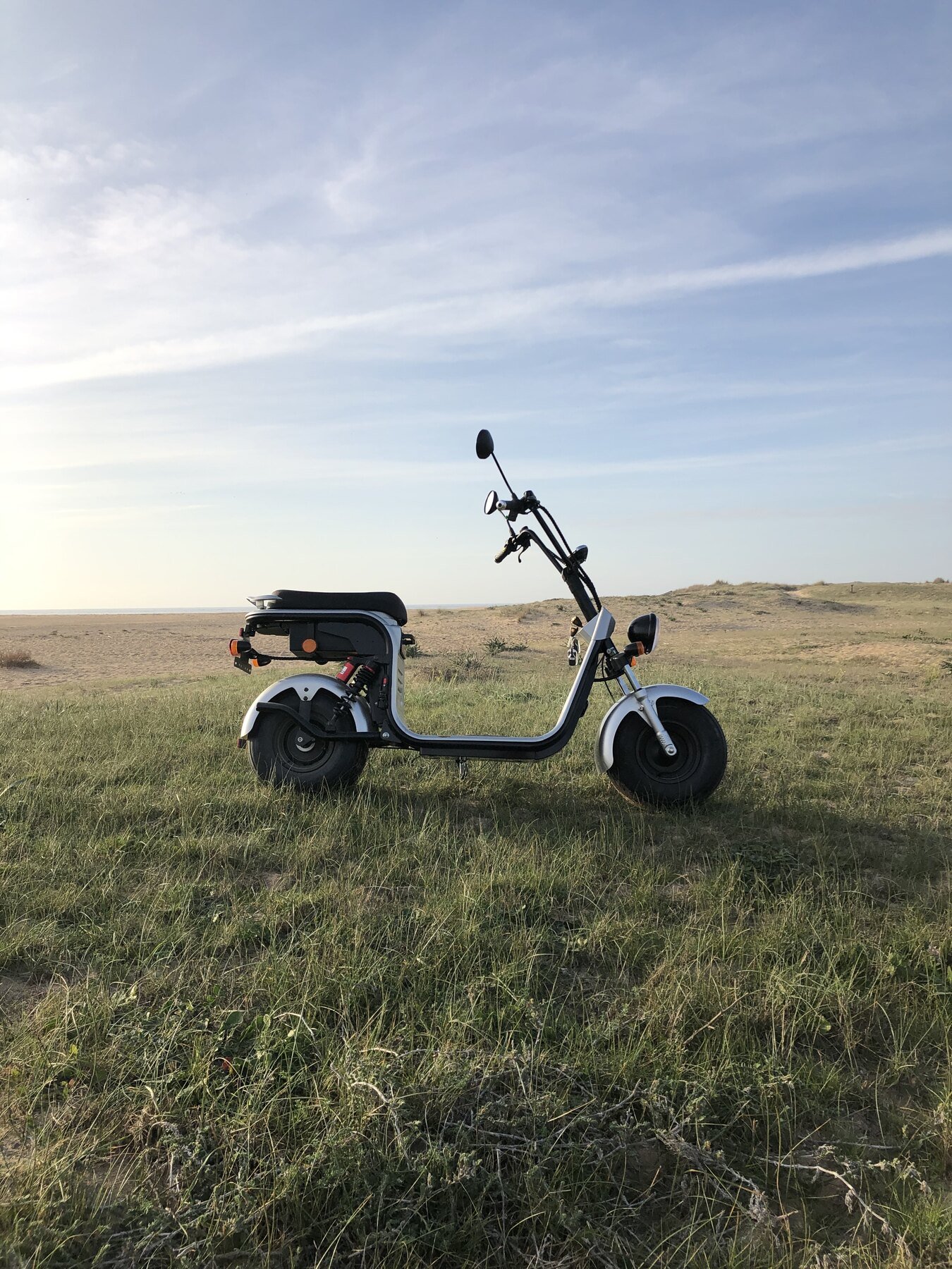 Scooter in a field under a big sky