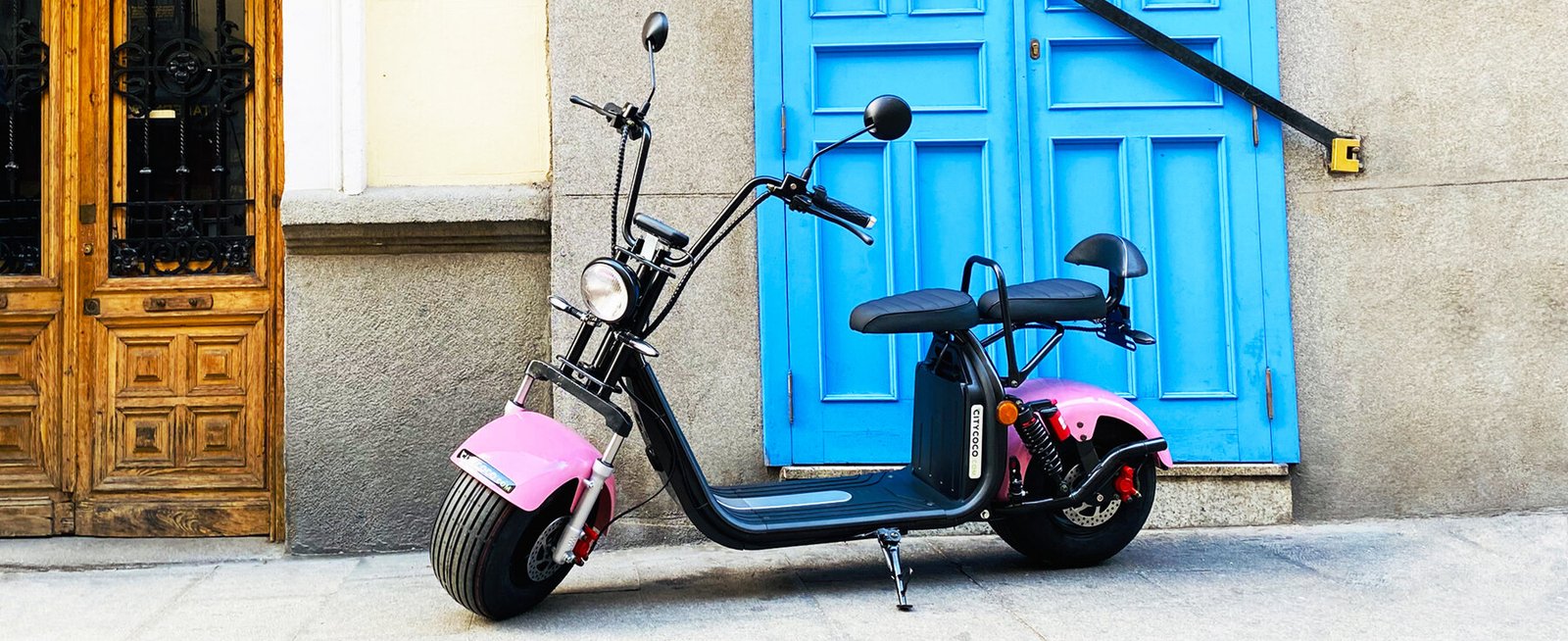 Pink Citycoco scooter against a blue door